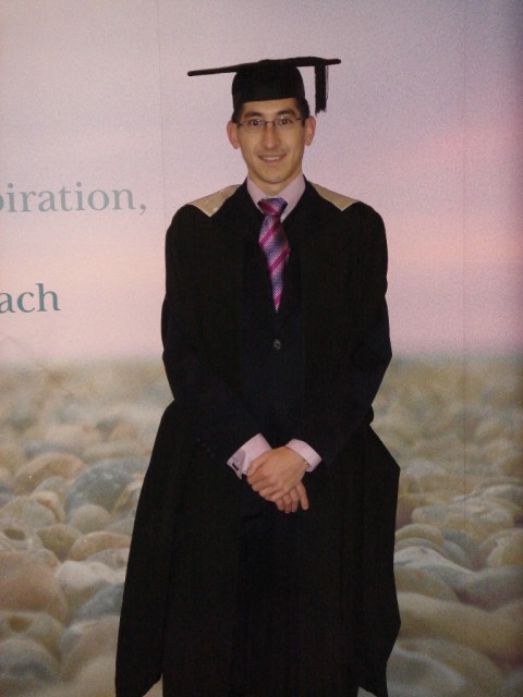 Aaron in the gown against the University of Sussex back-drop display. 